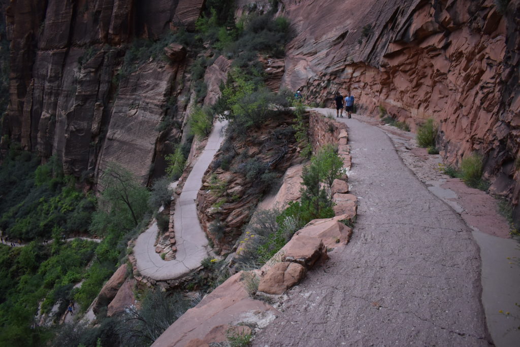 a group of people walking on a path in a canyon