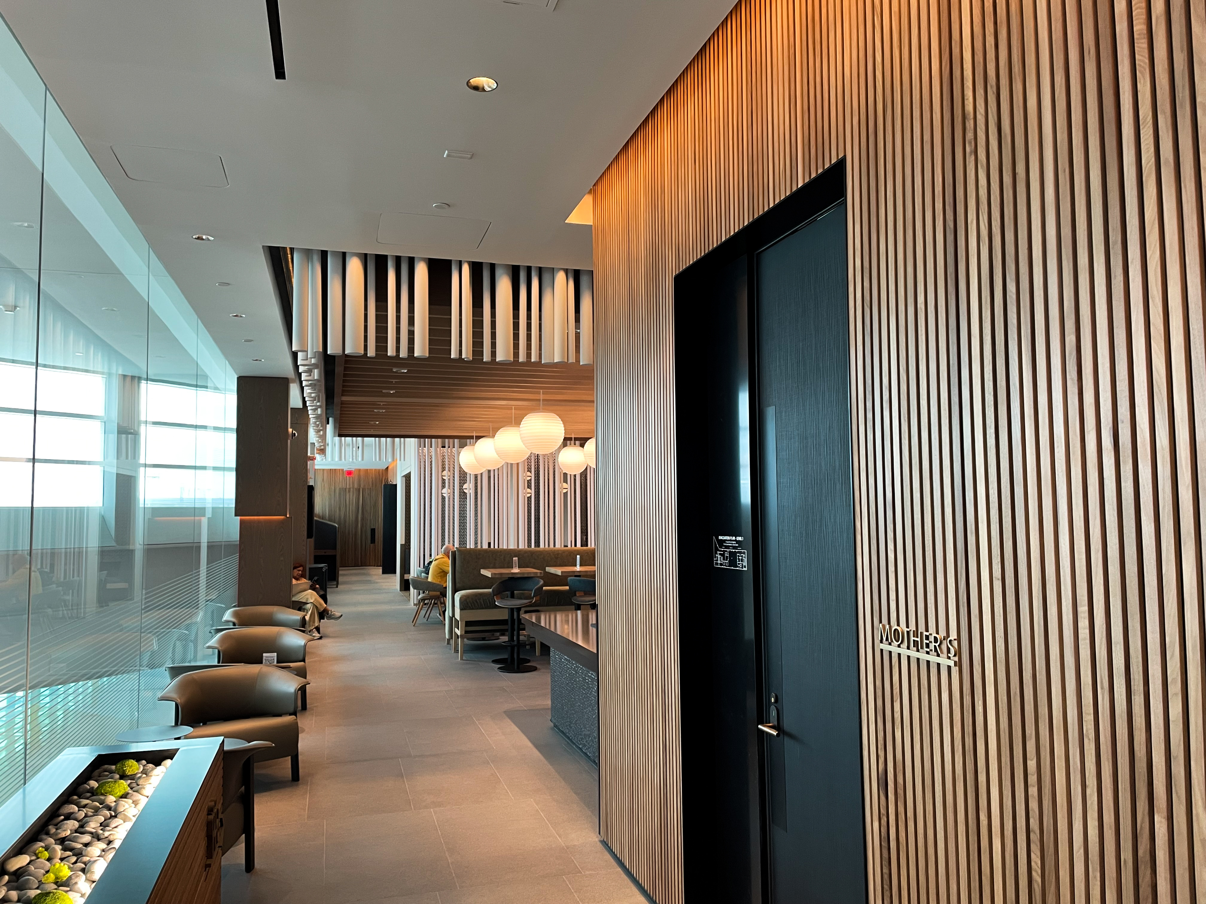 One of the main corridors leading to the bar and snack buffet at the Washington National Concourse E Admirals Club. The lounge utilizes elegant wood accents and features a warm and inviting color scheme.