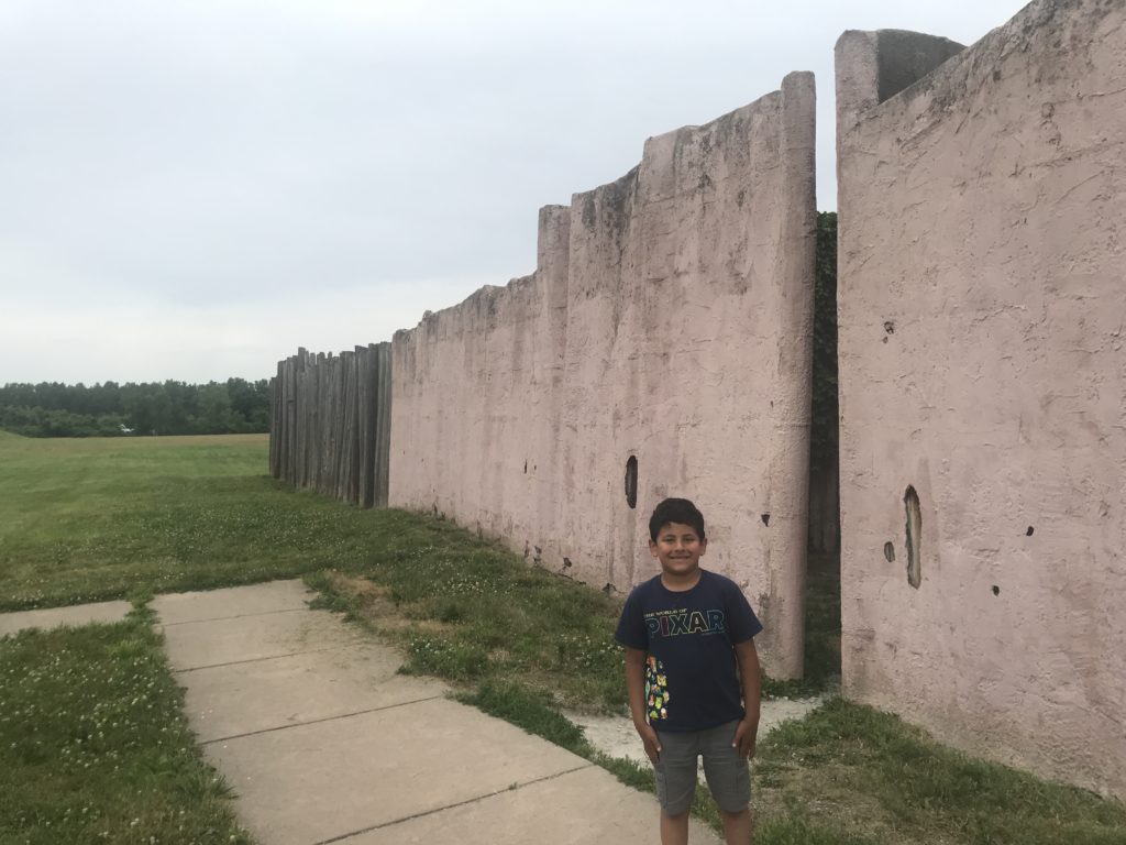 a boy standing in front of a stone wall