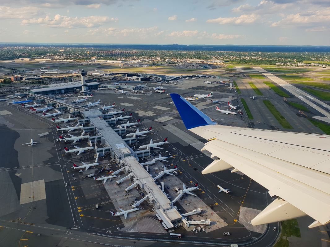 an airplane wing and a runway with airplanes in the background