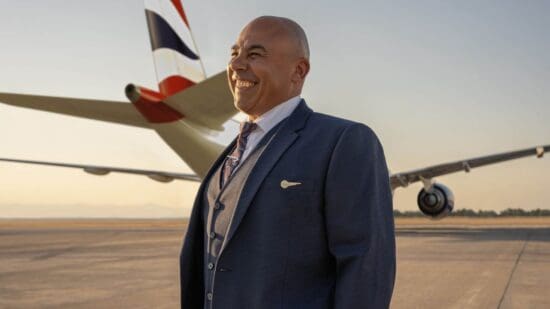 a man in a suit smiling in front of an airplane