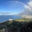 a rainbow over a city by the ocean