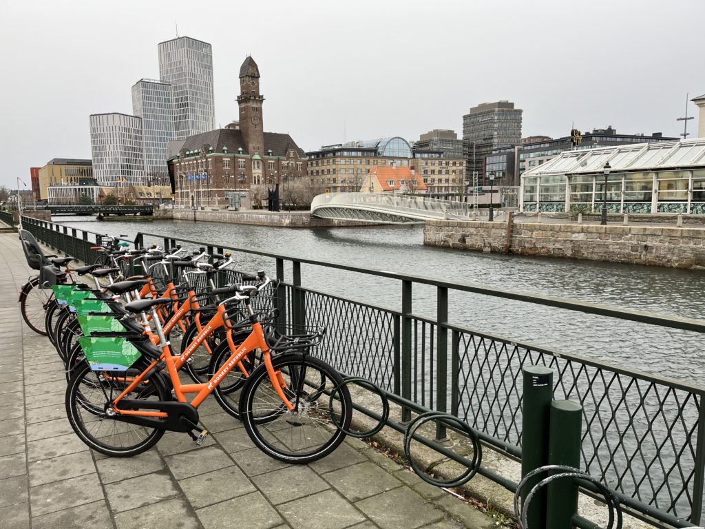 a row of bicycles parked on a sidewalk next to a river