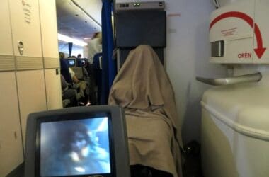 a person covered in a blanket on an airplane