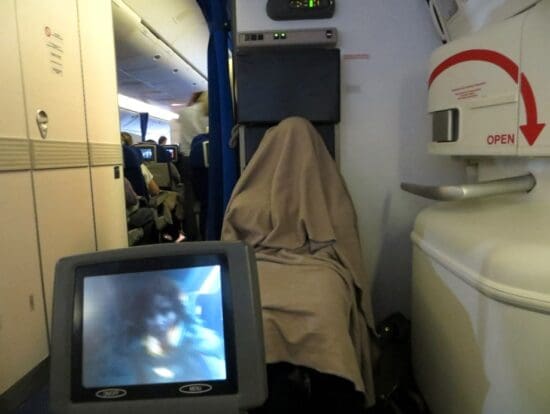 a person covered in a blanket on an airplane