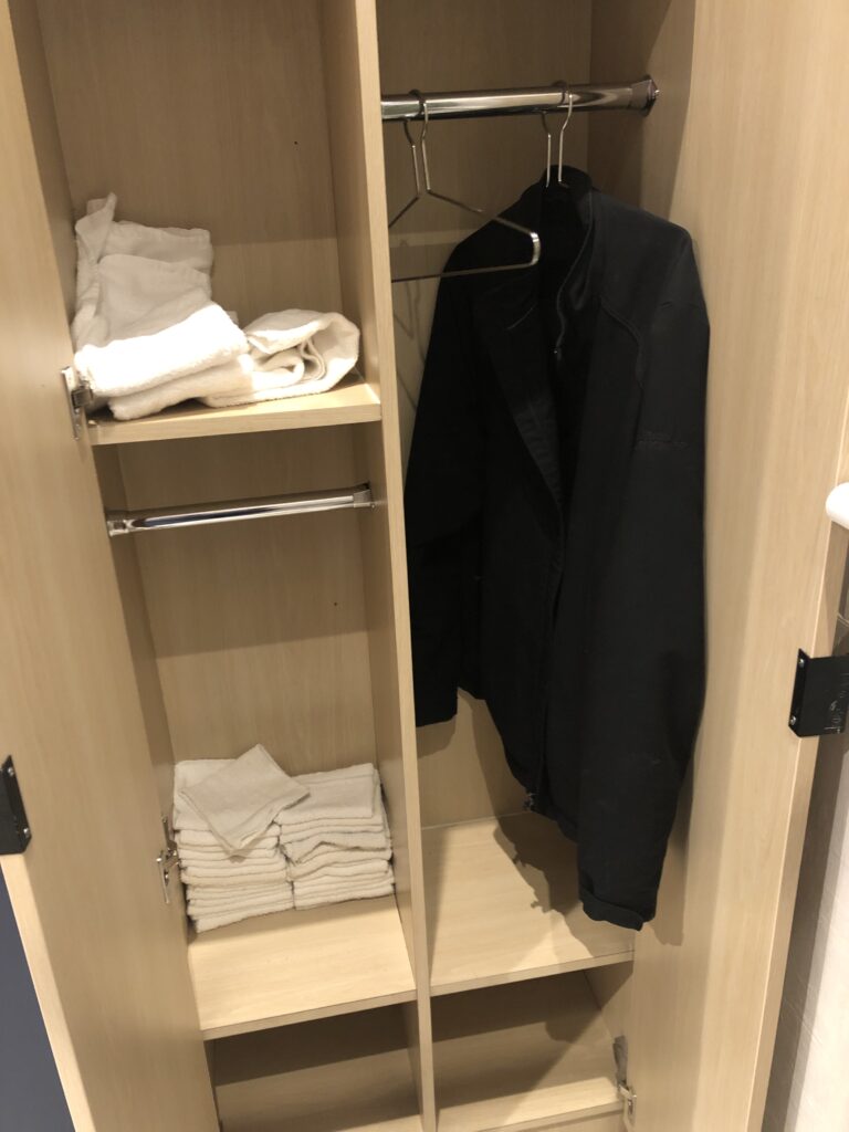 a closet with a coat and towels