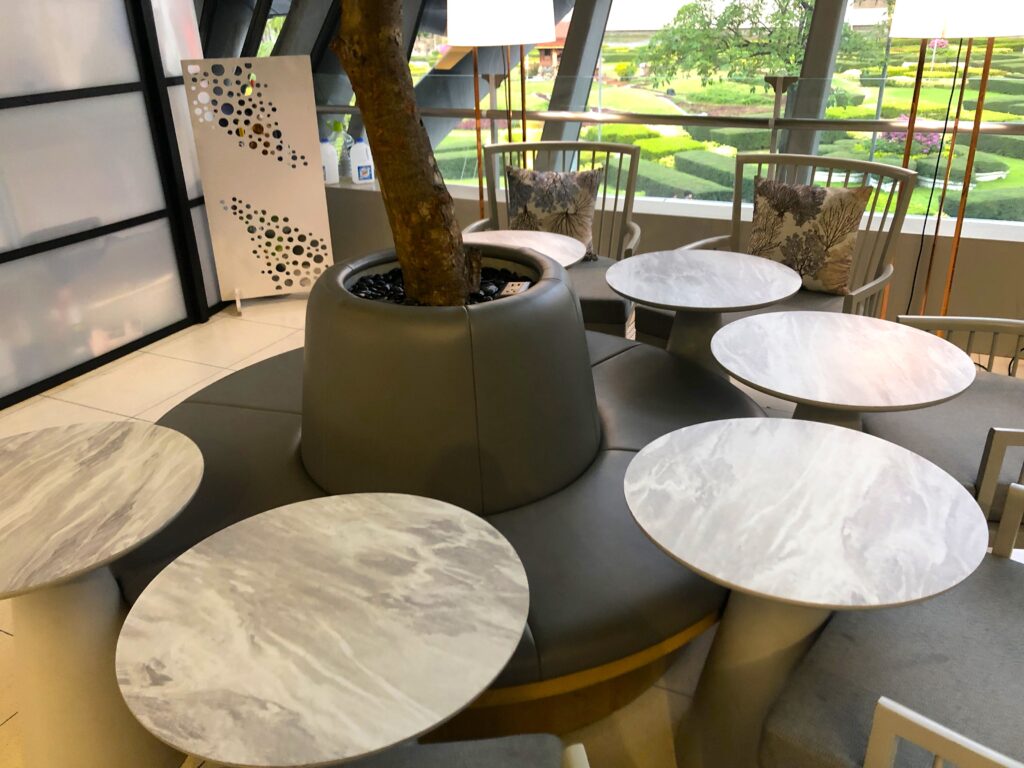 Interesting seating arrangement with a round bench set around a tree and 6 tables pushed against the bench.