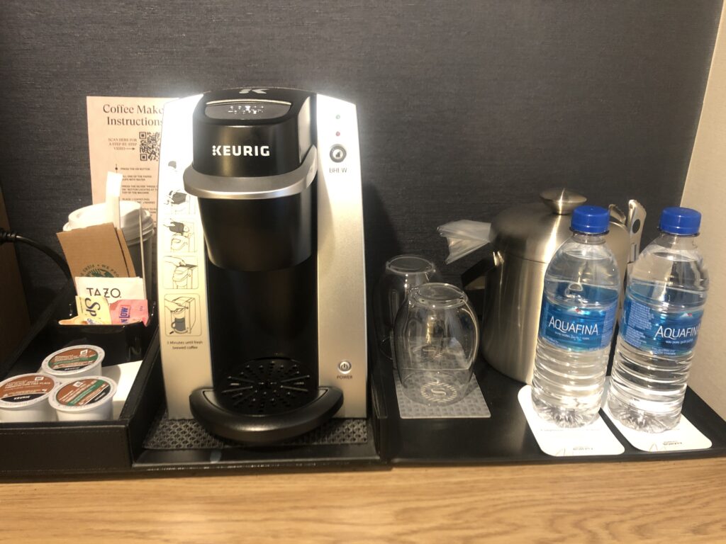 a coffee maker and water bottles on a tray