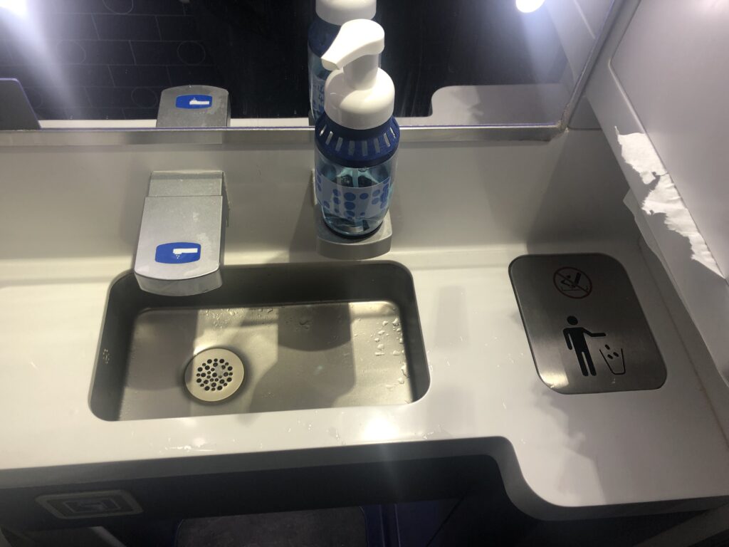 a sink with a bottle of liquid and a sign on it