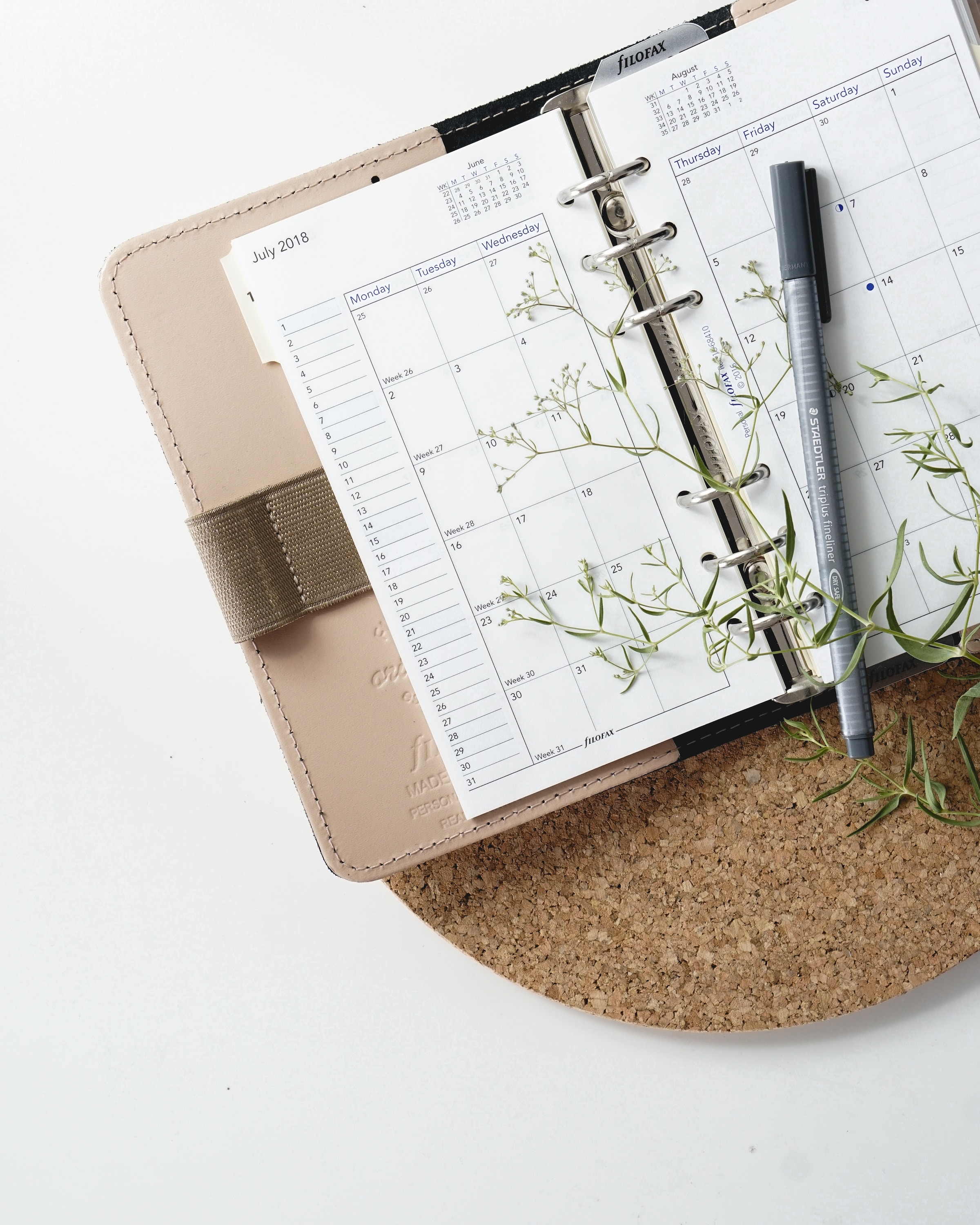 a calendar and pen on a cork pad