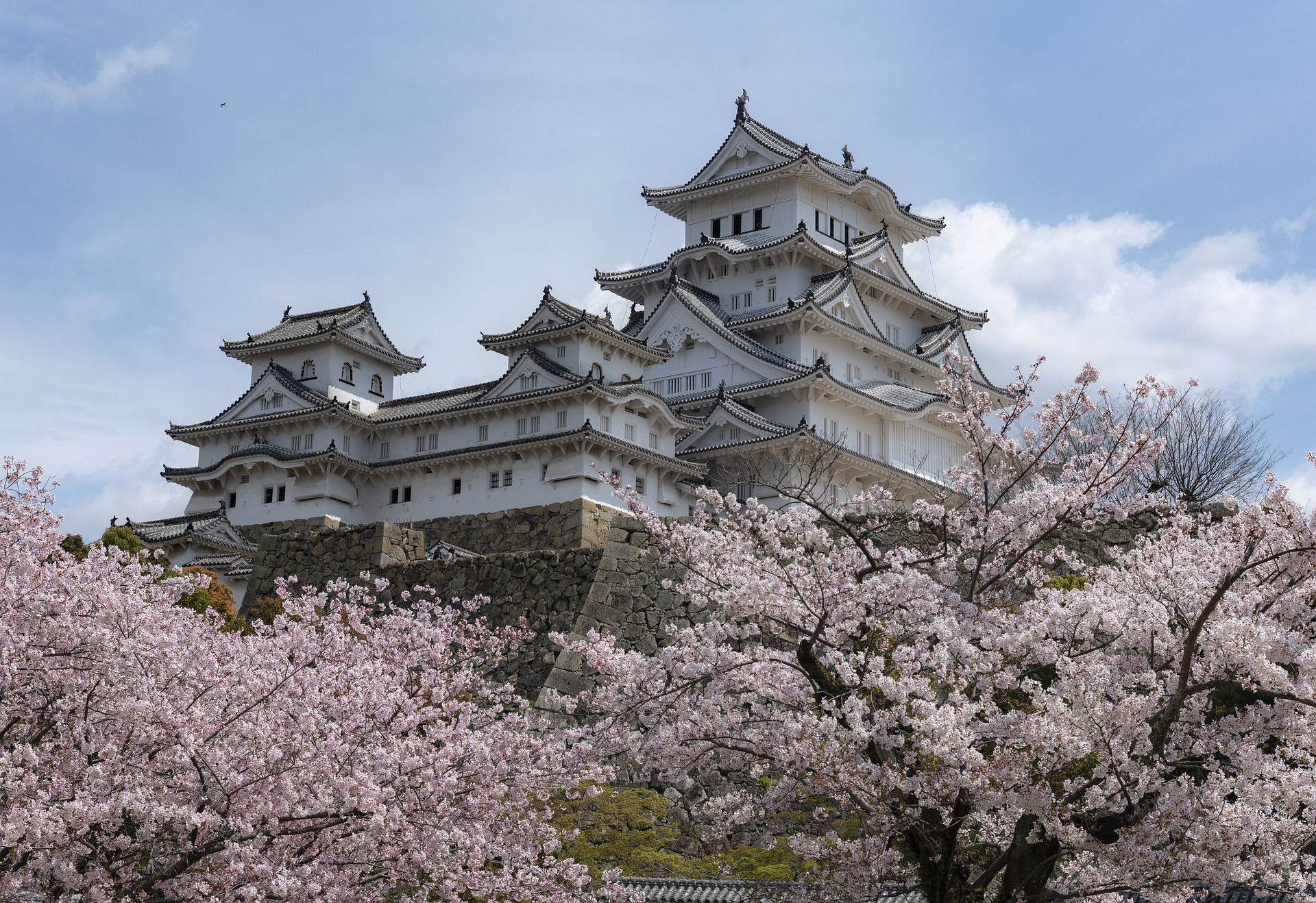 a white building with a few trees in front of it with Himeji Castle in the background