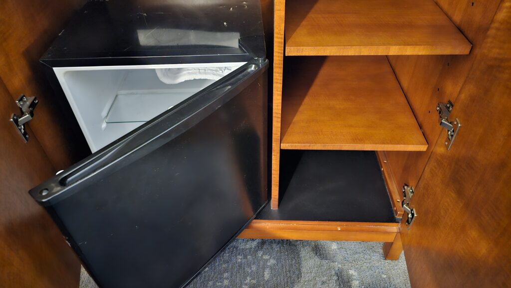 a black refrigerator with a wooden shelf