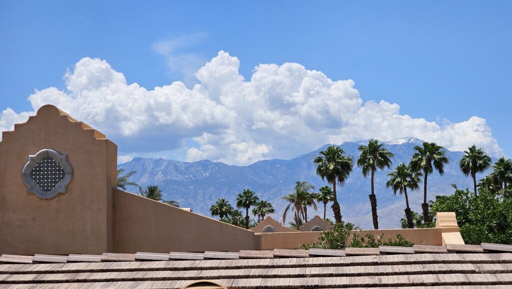 a roof of a building with palm trees and mountains in the background