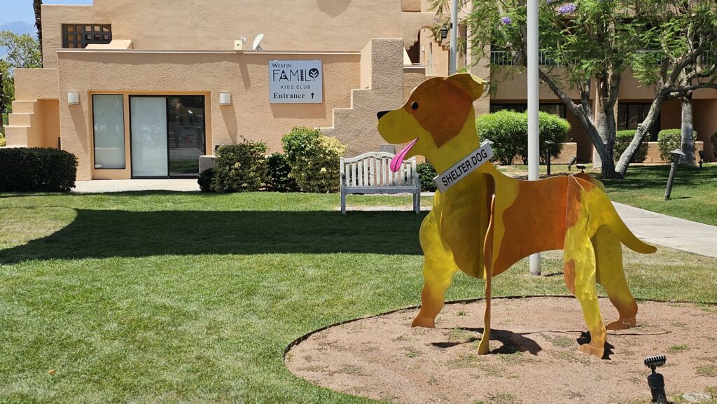 a yellow dog statue in a grassy area