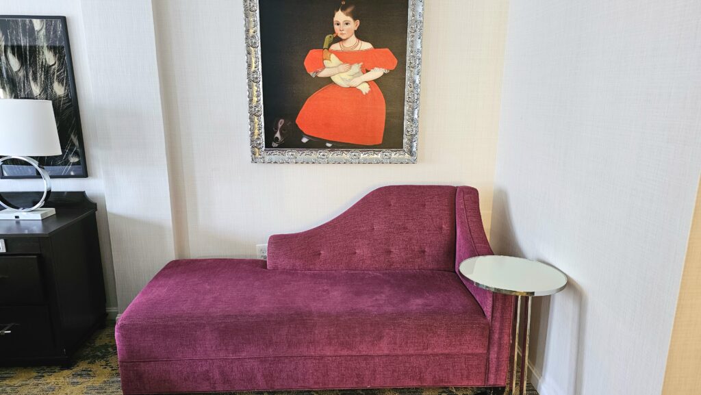 a purple couch with a table and a painting on the wall