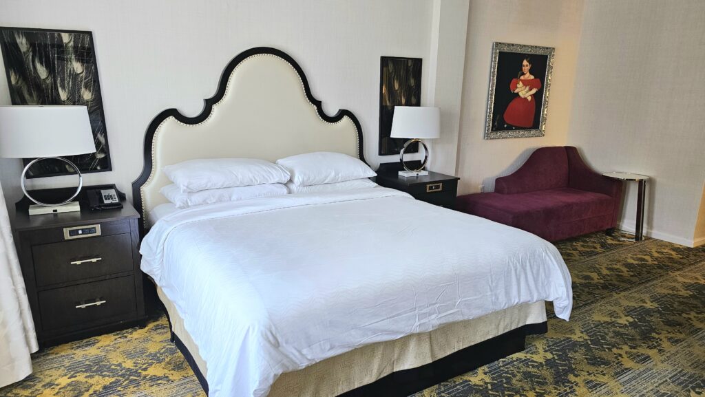 a bed with a white bedding and a red chair