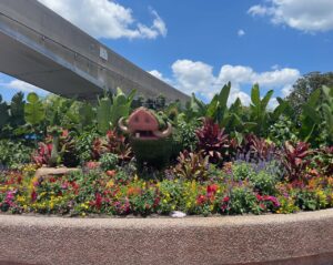 a flower bed with plants and a bridge in the background