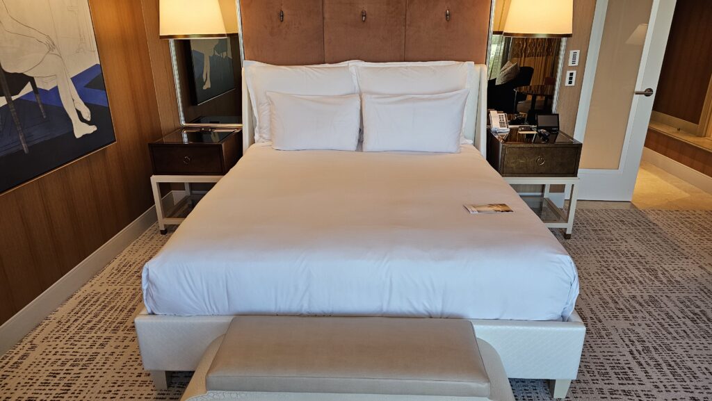 a bed with white sheets and a foot stool