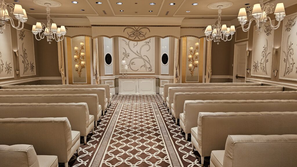 a room with white chairs and chandeliers