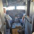 a cockpit of an airplane with a few men sitting in the cockpit