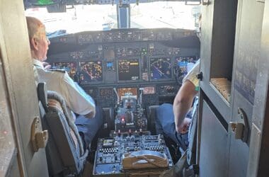 a cockpit of an airplane with a few men sitting in the cockpit