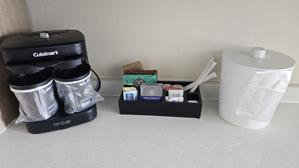 a coffee maker and a container with condiments