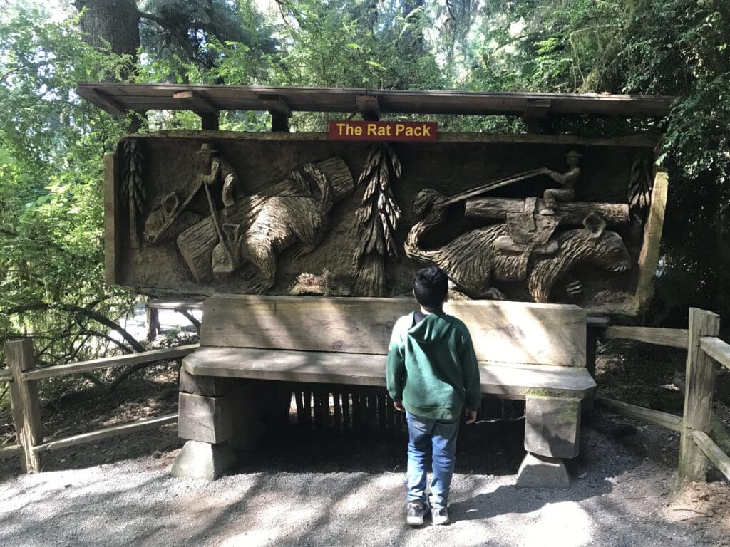 a boy standing in front of a bench with a sculpture of animals