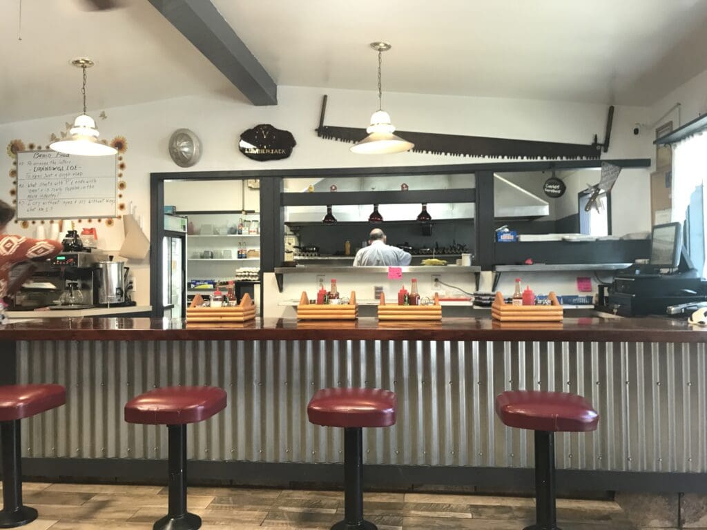 a bar with stools and a man behind it