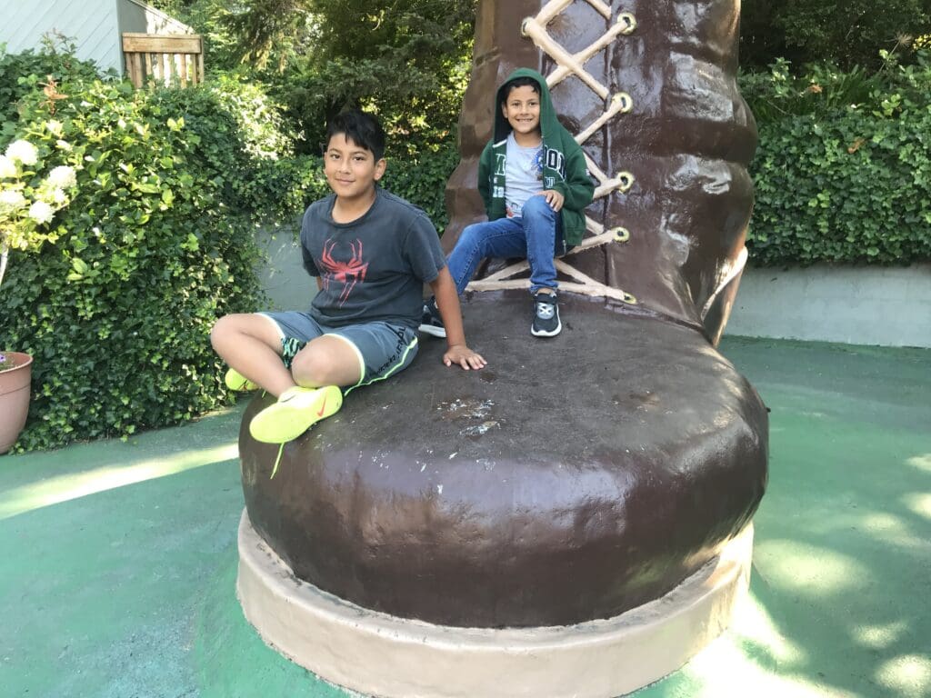 two boys sitting on a statue of a boot