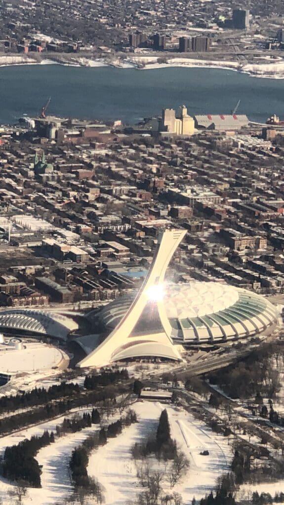 a large white structure with a pointed roof and a city in the background