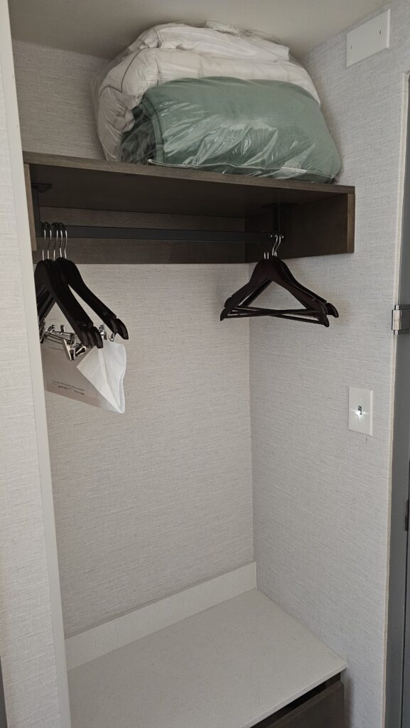 a closet with swingers and a blanket on top