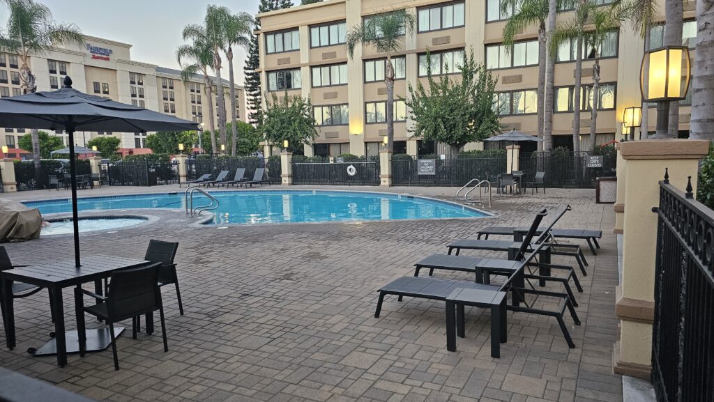 a pool with chairs and umbrellas in front of a building