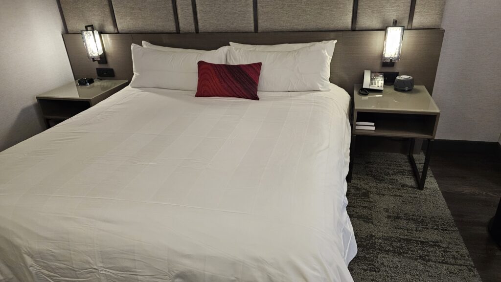 a bed with a white sheet and a red pillow