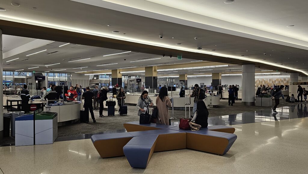 people in an airport with people waiting for their luggage