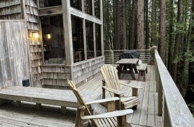 a wooden deck with chairs and a table in the woods