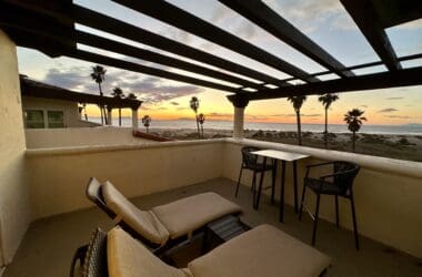 a deck with chairs and a table and a table with a view of the ocean