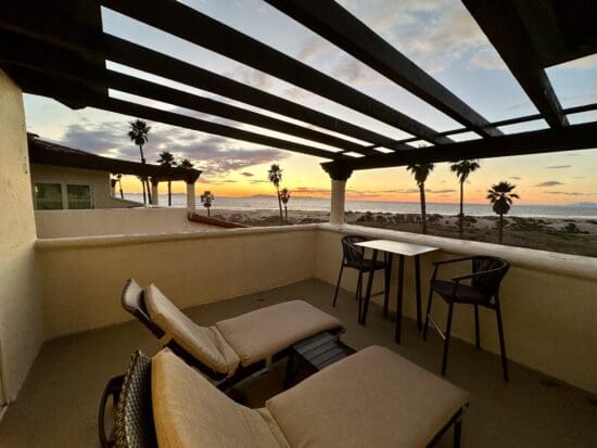 a deck with chairs and a table and a table with a view of the ocean