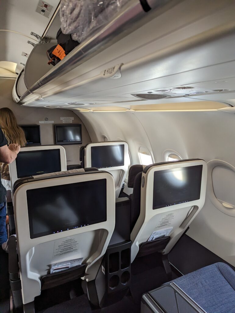 a row of seats with monitors on the side of the plane