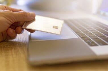 a hand holding a credit card over a laptop