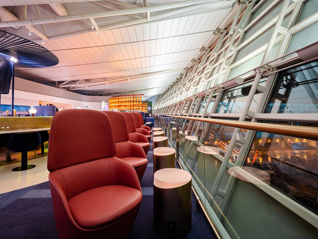 a row of red chairs in a room with a glass railing