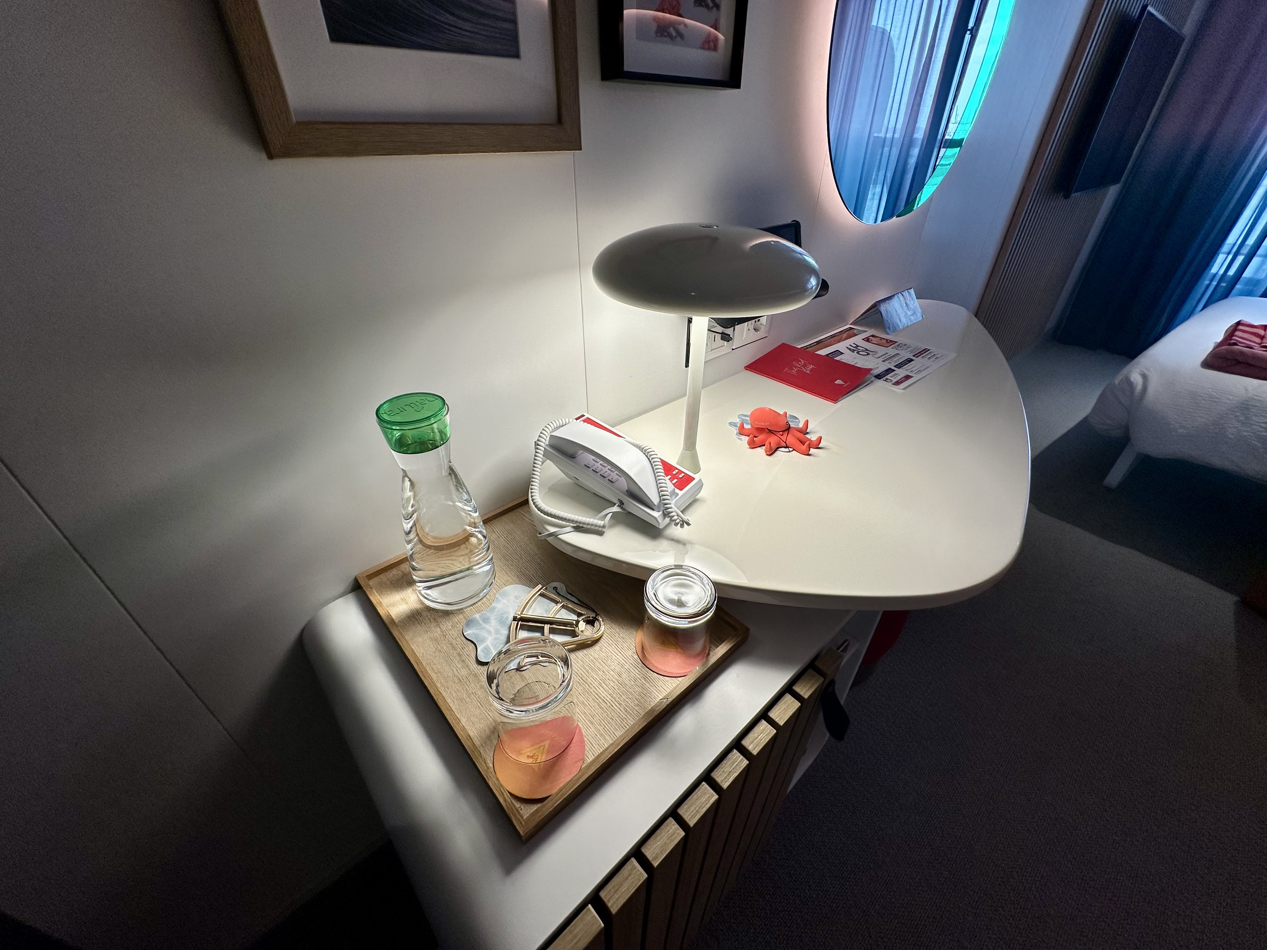 a table with a lamp and glasses on it in a Virgin Voyages Sea Terrace Cabin