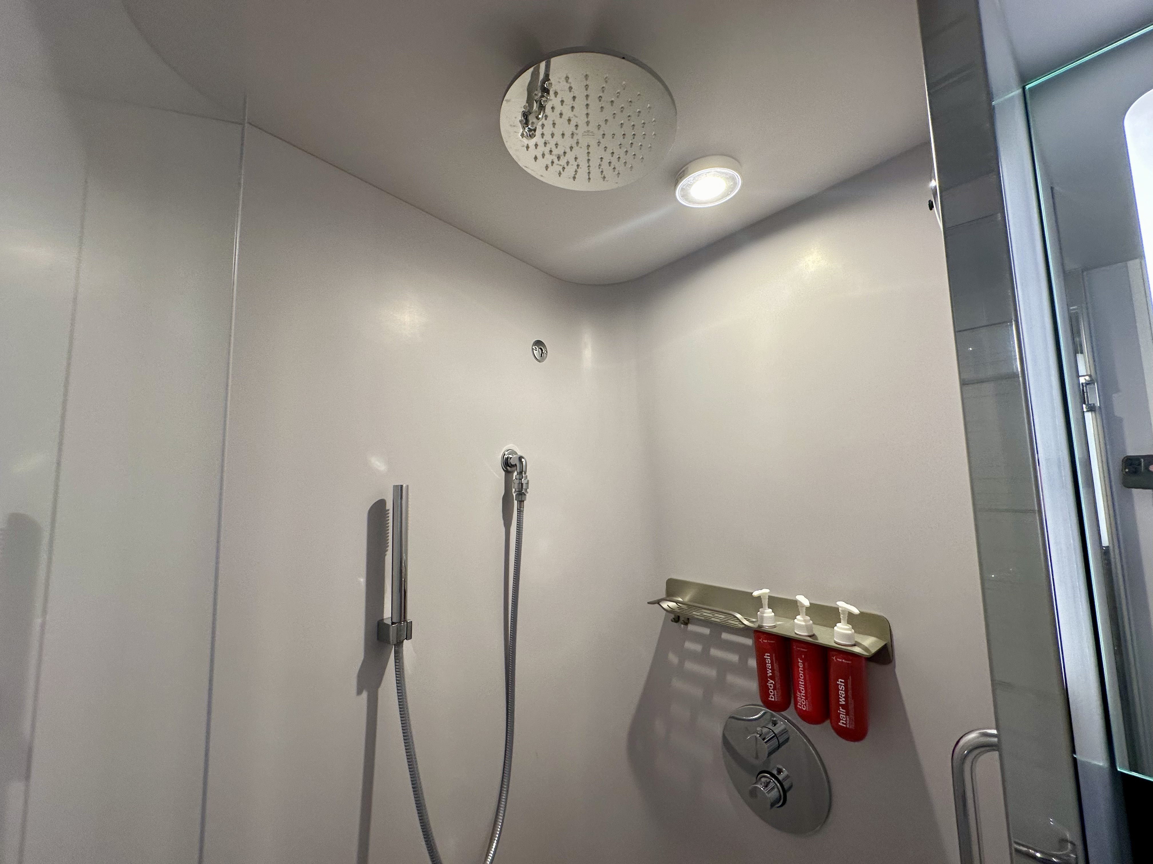 a shower with a shower head and wand on a Virgin Voyages Sea Terrace Cabin