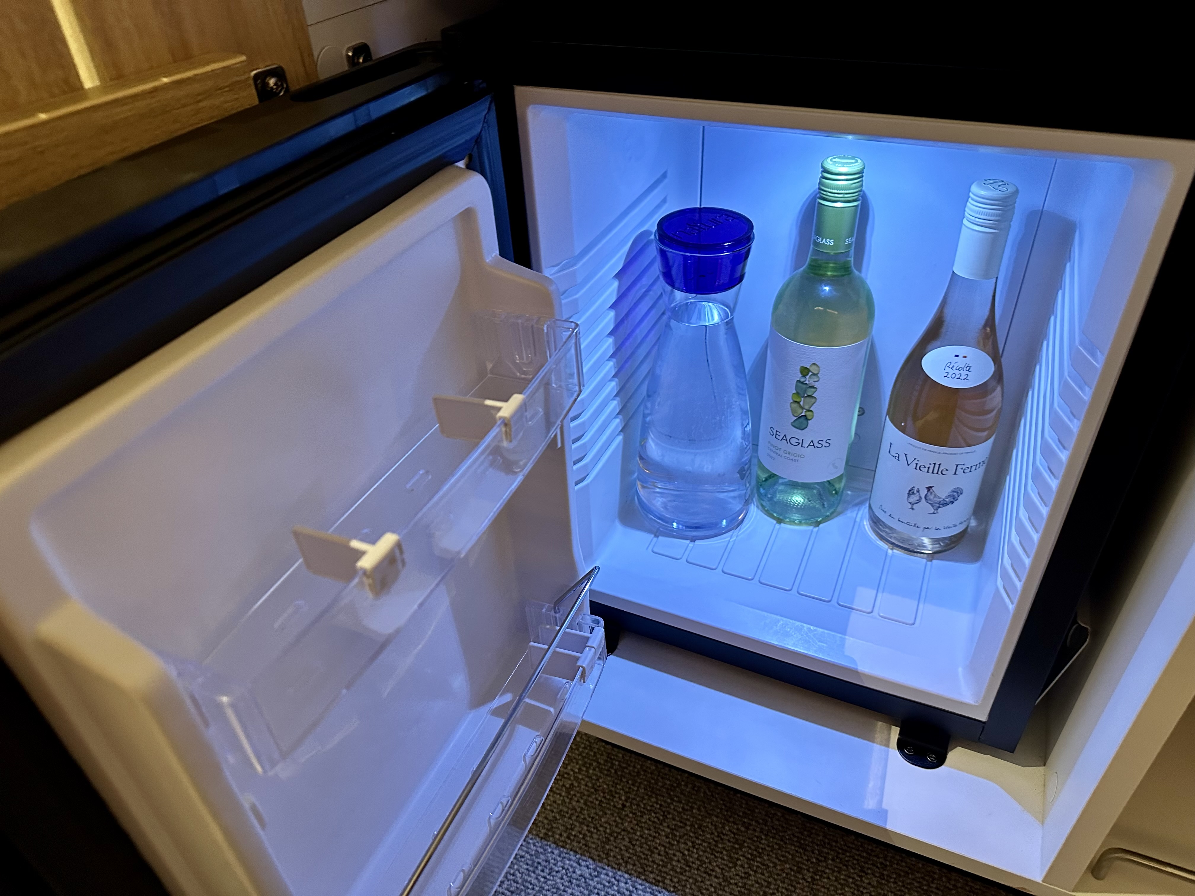 a mini fridge with bottles of wine inside