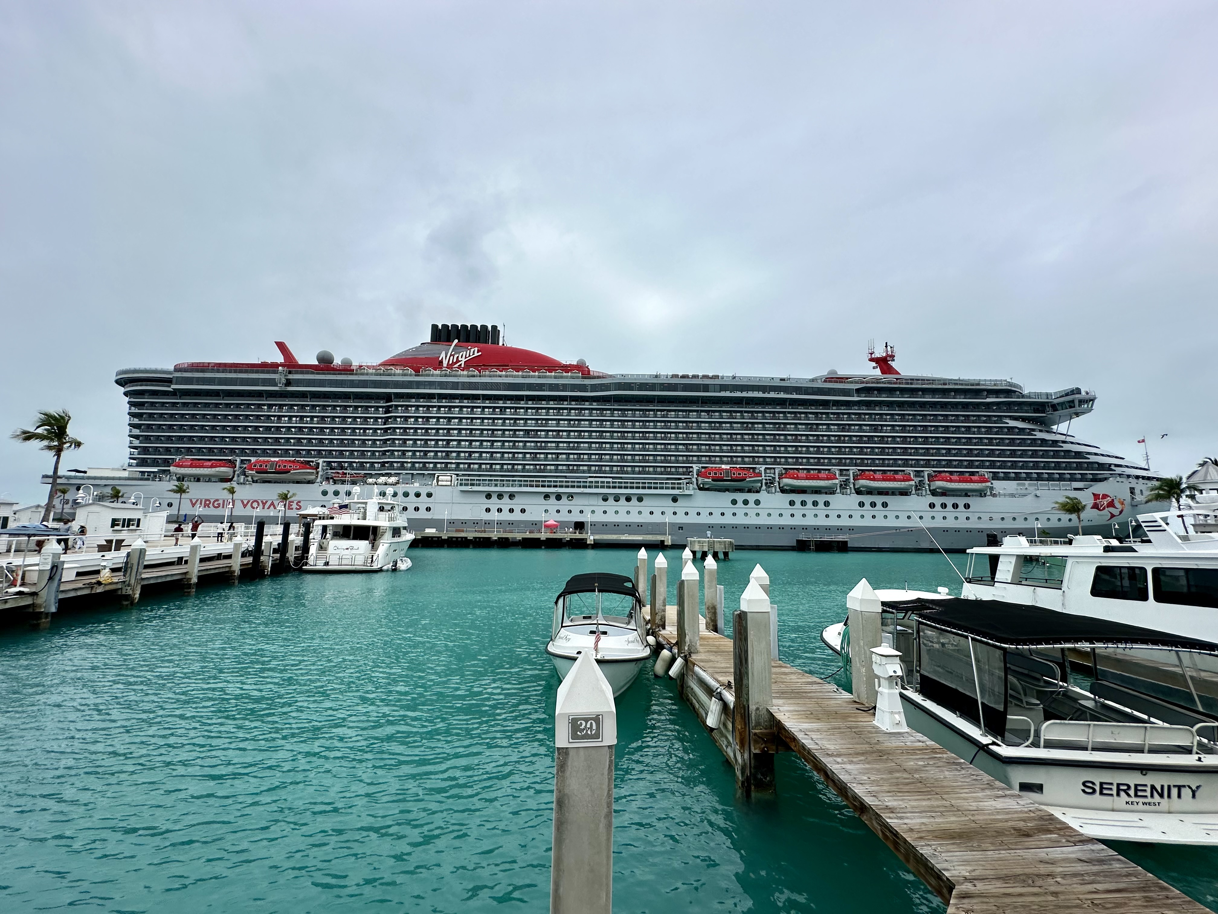 a Virgin Voyages cruise ship docked in a harbor