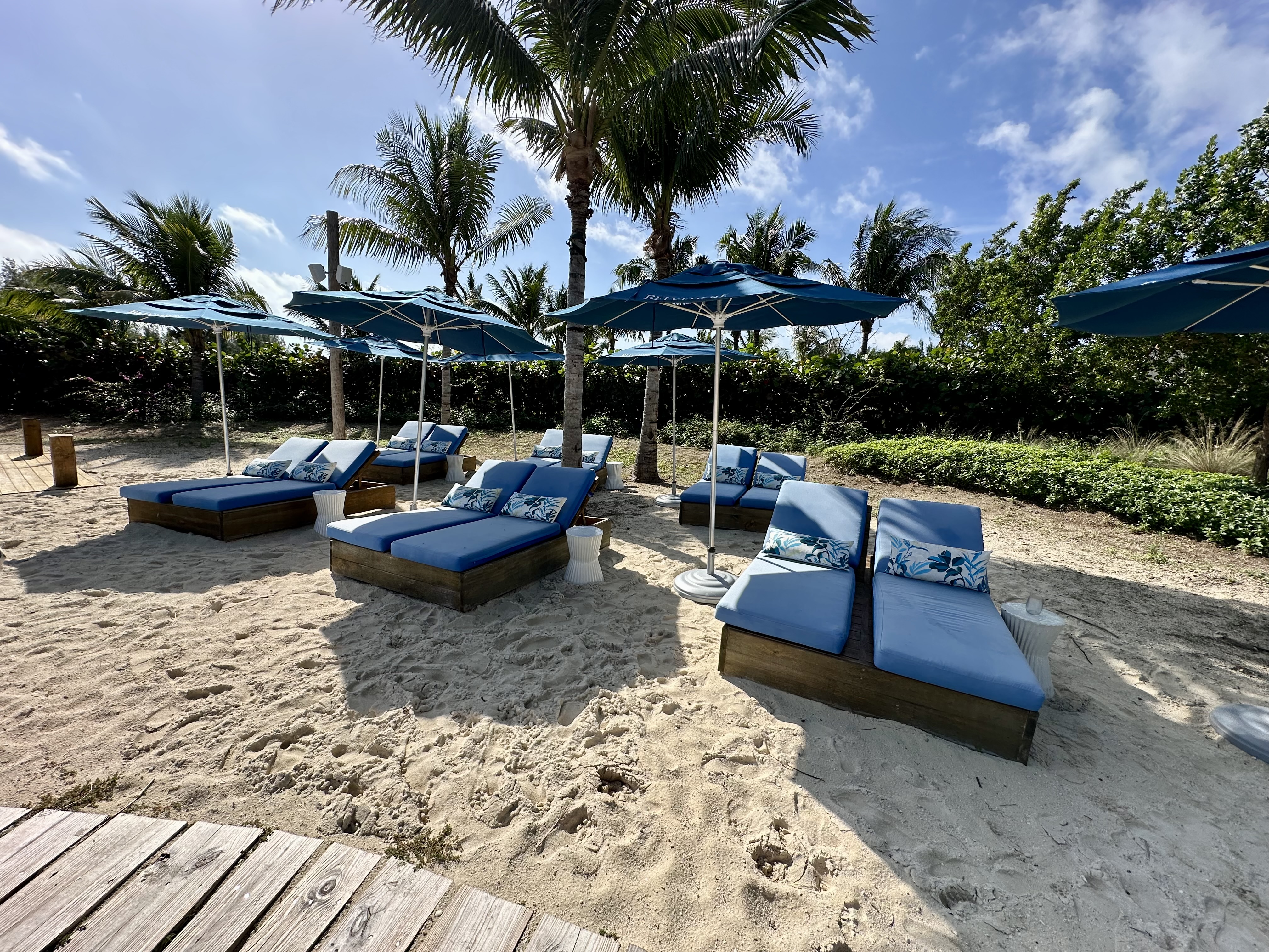 a group of blue lounge chairs and umbrellas on a beach