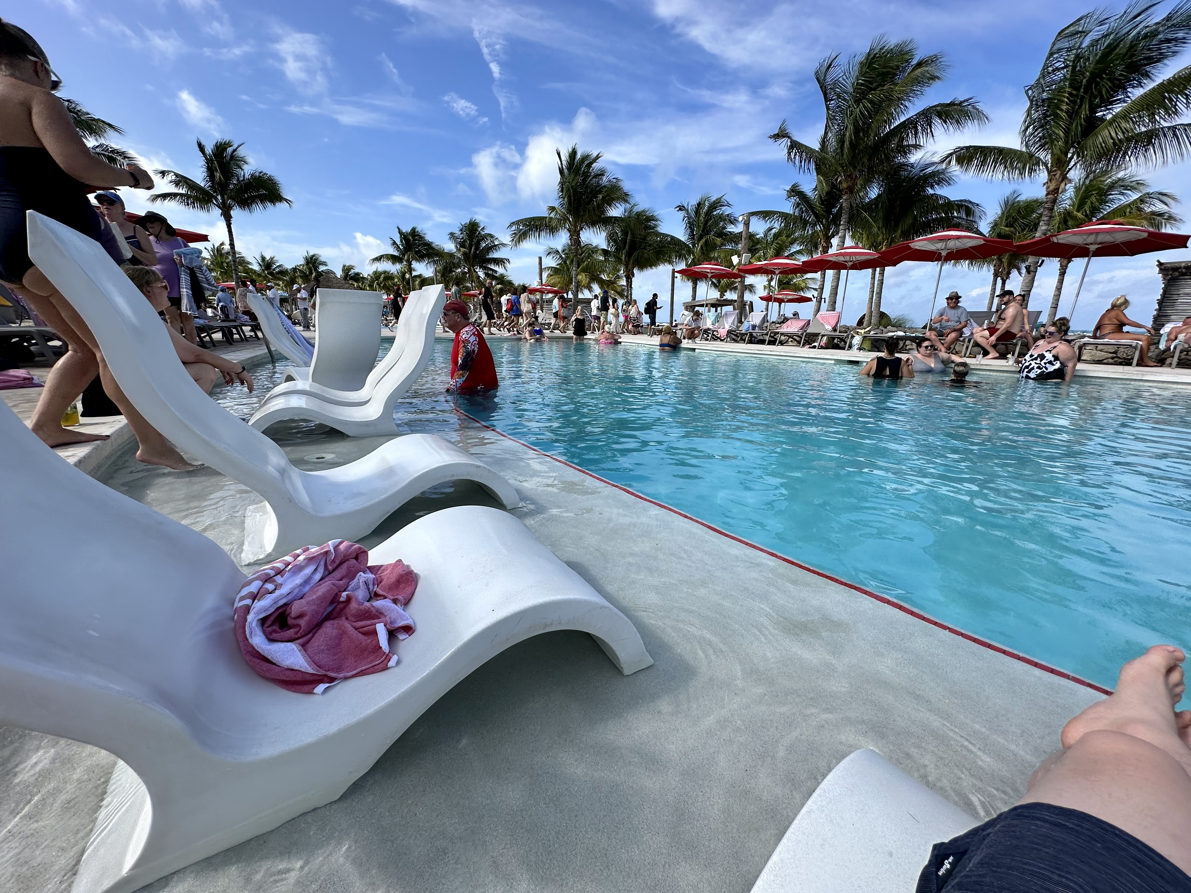 a pool with chairs and people in the background