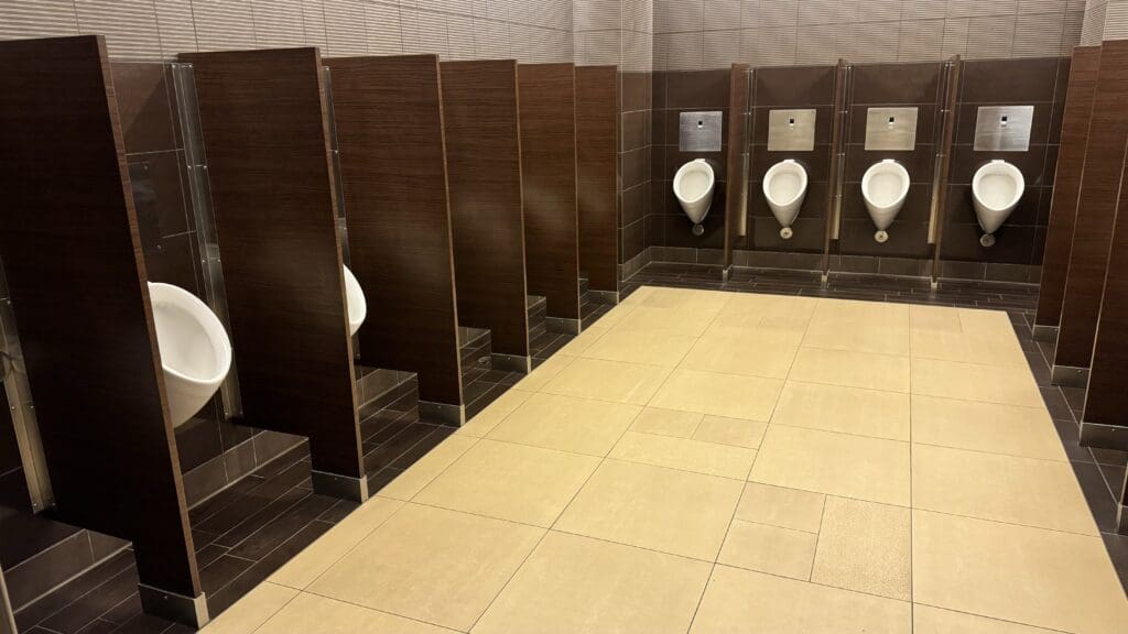 a bathroom with urinals and brown walls