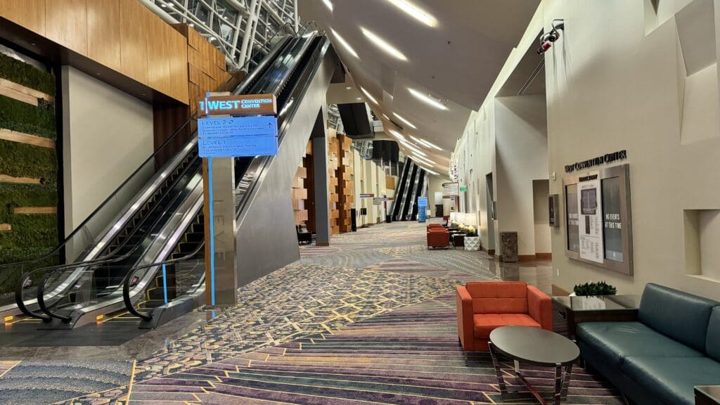 an empty lobby with an escalator and an orange chair