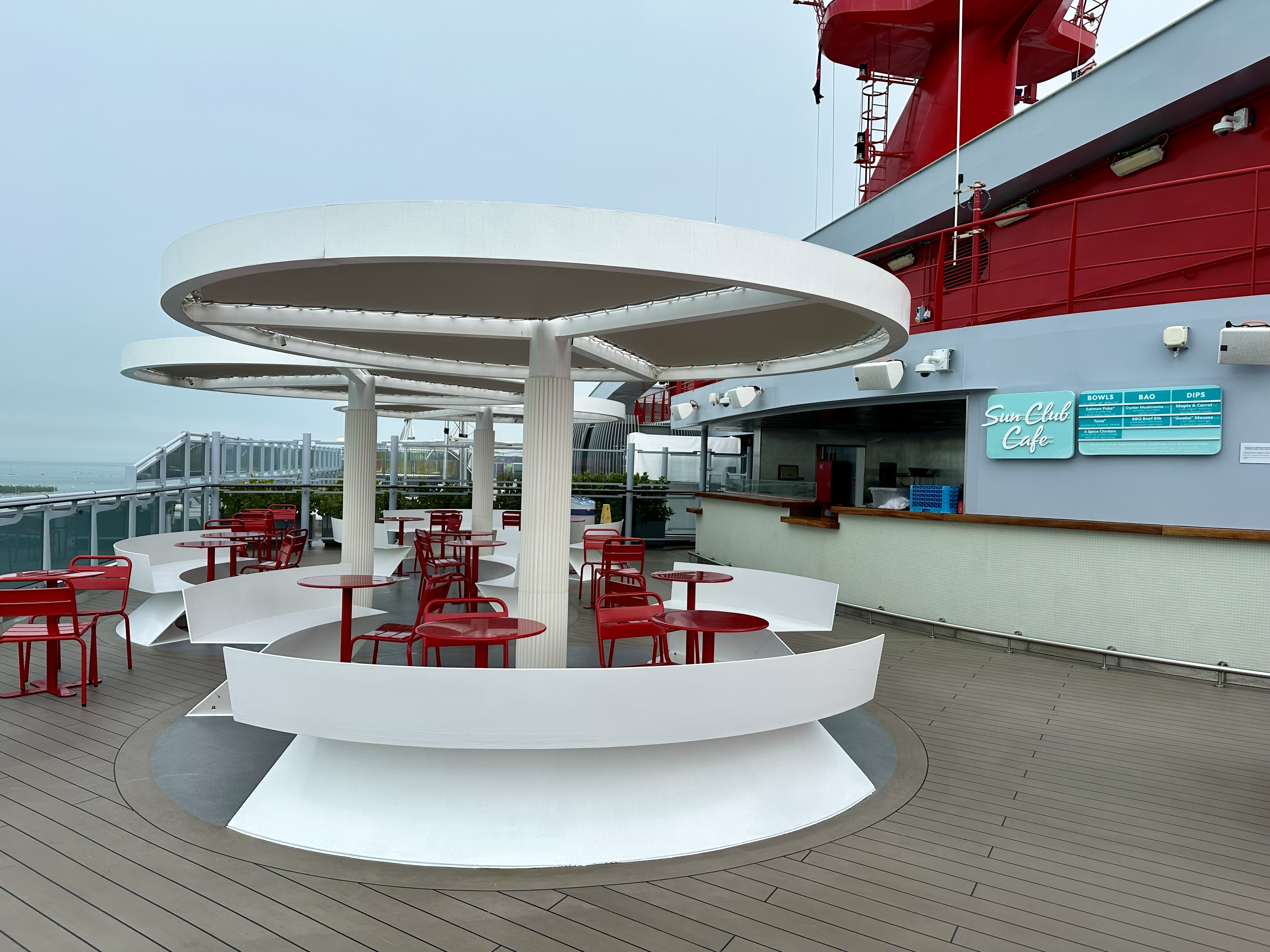 a white tables and chairs on a deck of a cruise ship