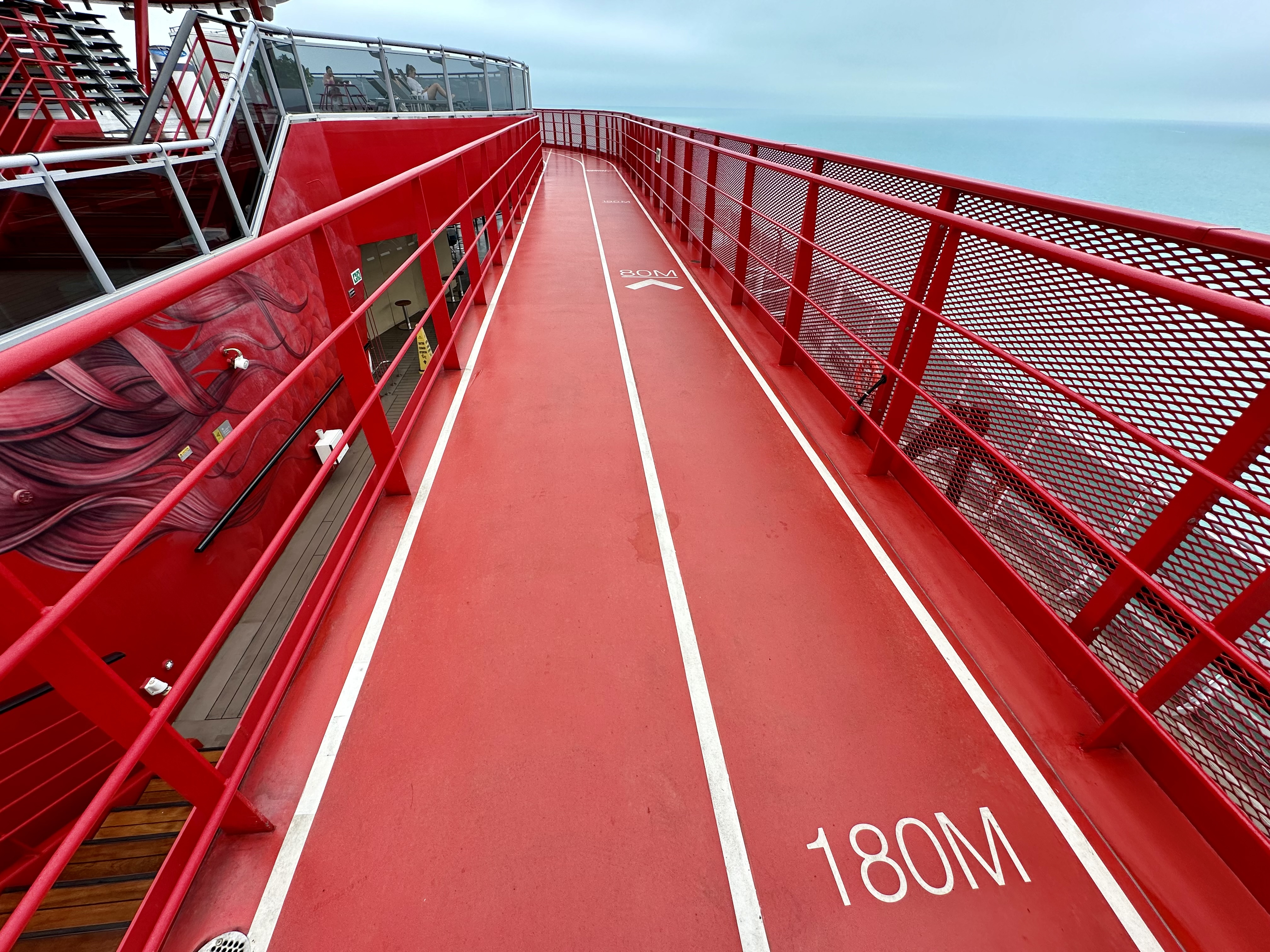 a red walkway with white lines and a red railing